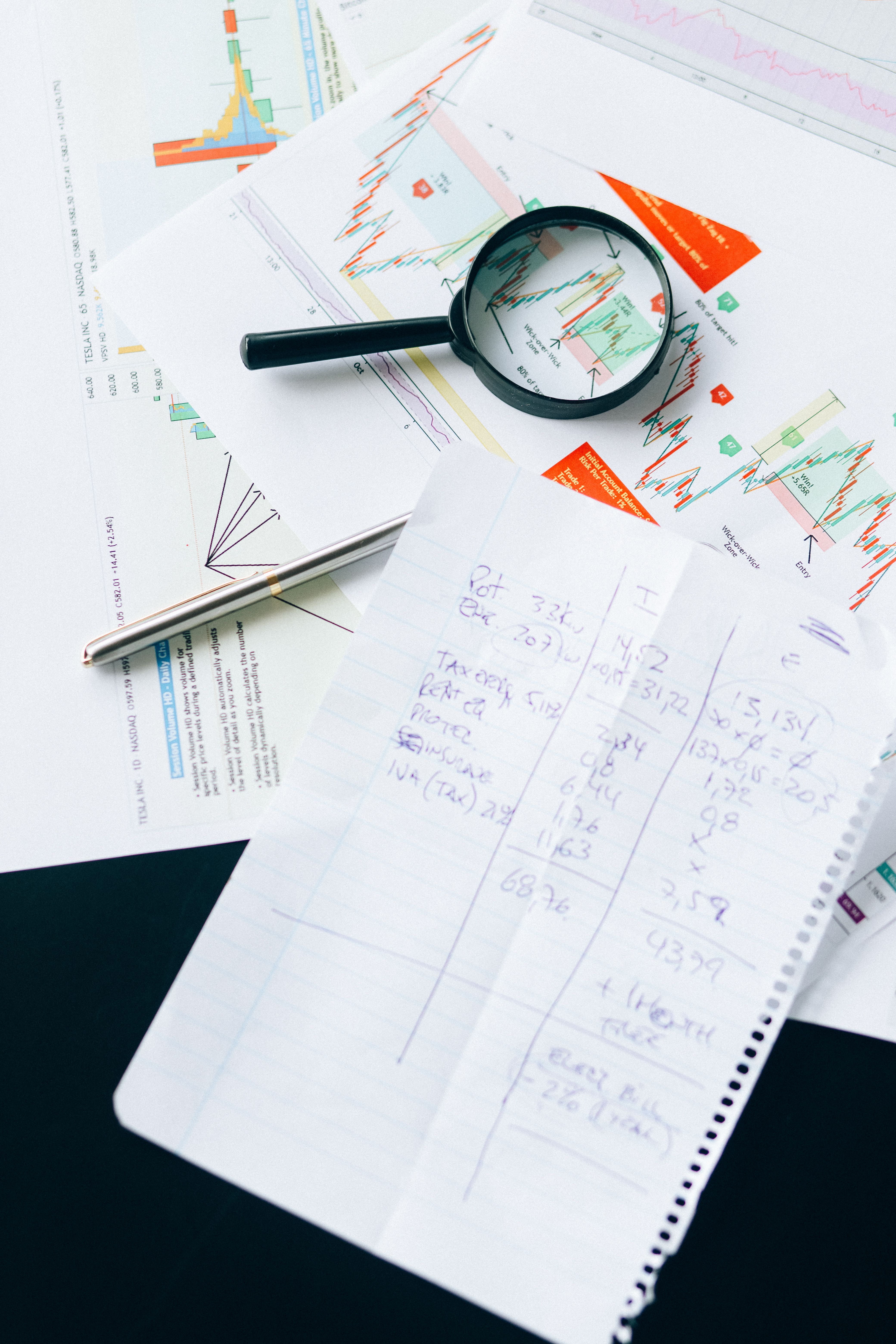 Financial charts and notes spread across a desk for analysis.